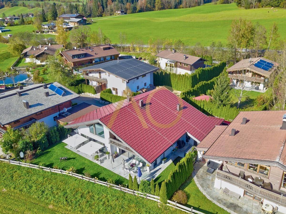 Luftaufnahme der Villa mit großzügiger Terrasse, Garten und umgebender grüner Landschaft.