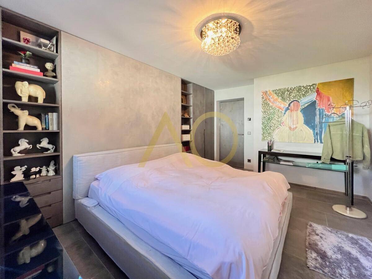 Geräumiges Schlafzimmer mit modernem Bett, Kunstwerken und integrierten Regalen.