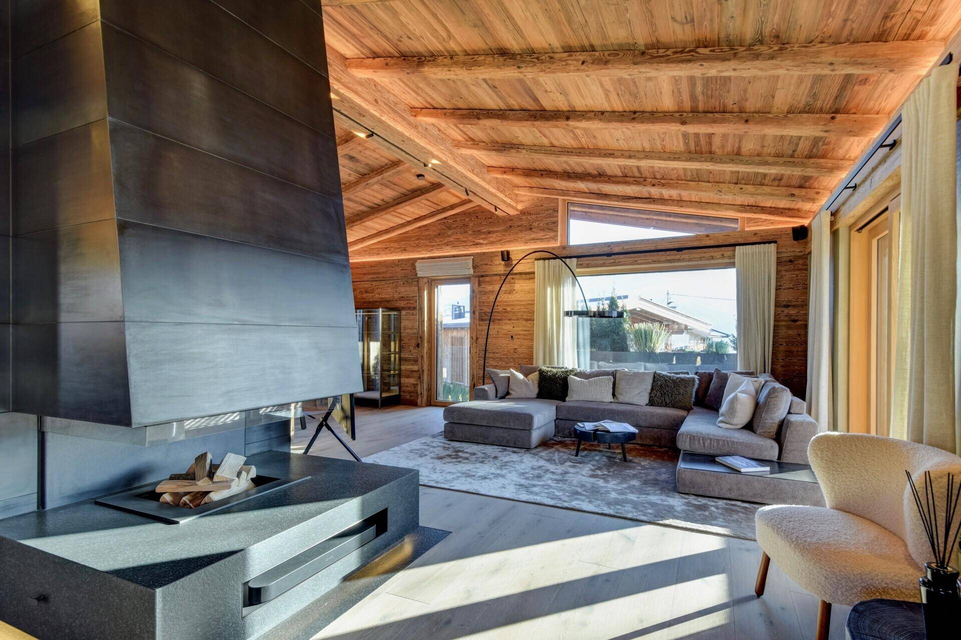 Geräumiges Wohnzimmer mit Kamin, großer Couch und Bergblick, hell und einladend gestaltet.