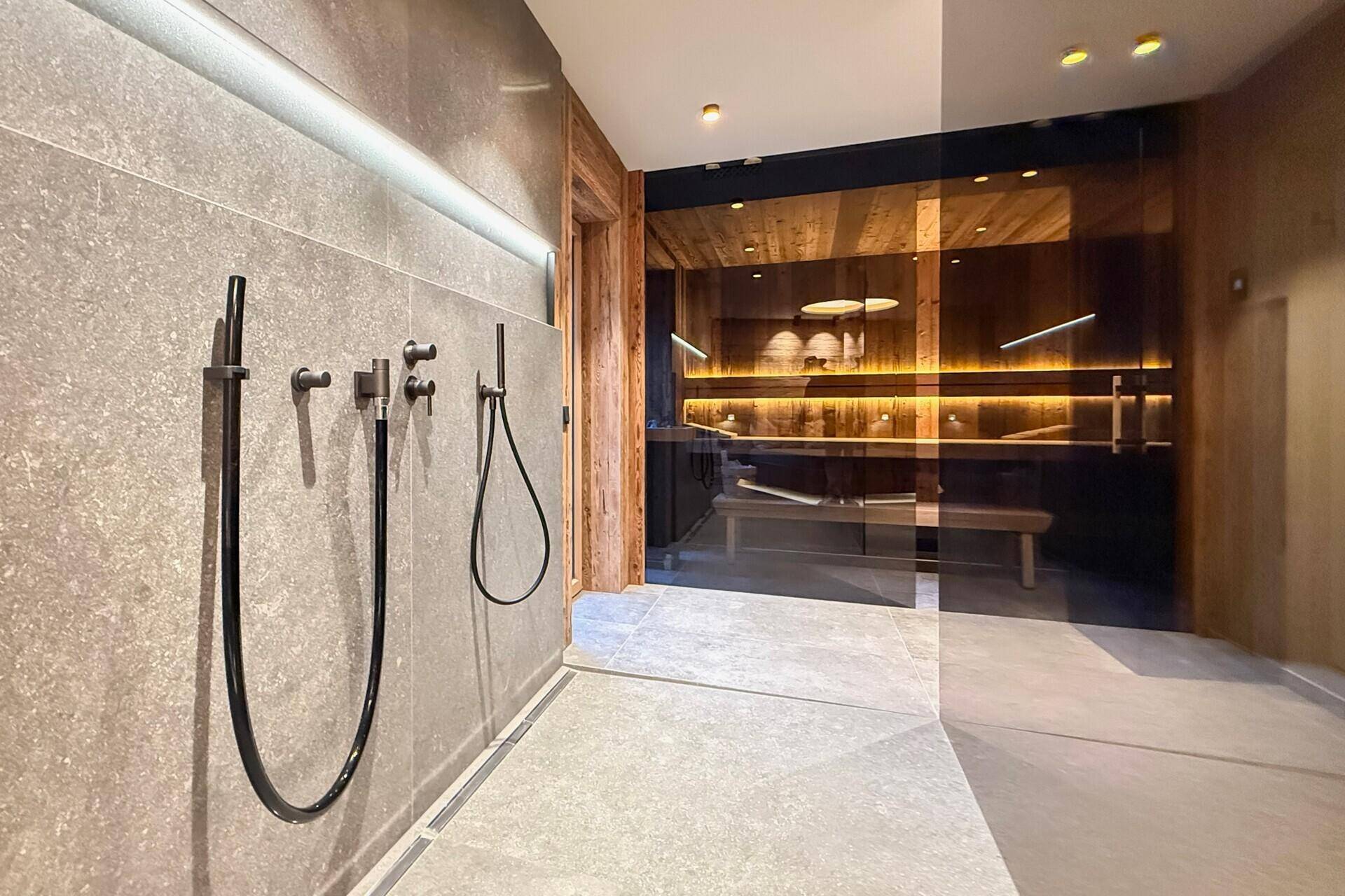Moderner Duschbereich mit Zugang zur Sauna, Teil eines luxuriösen Wellnessbereichs.