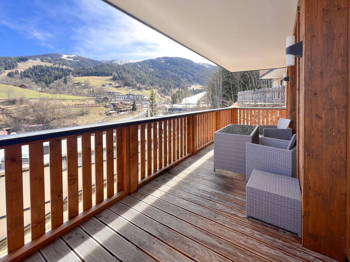 Sonniger Balkon mit bequemen Outdoor-Möbeln und einem weiten Blick auf die Berglandschaft.
