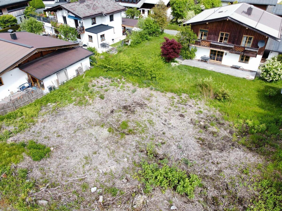 Luftaufnahme eines gerodeten Grundstücks, umgeben von grünen Wiesen und benachbarten Häusern.