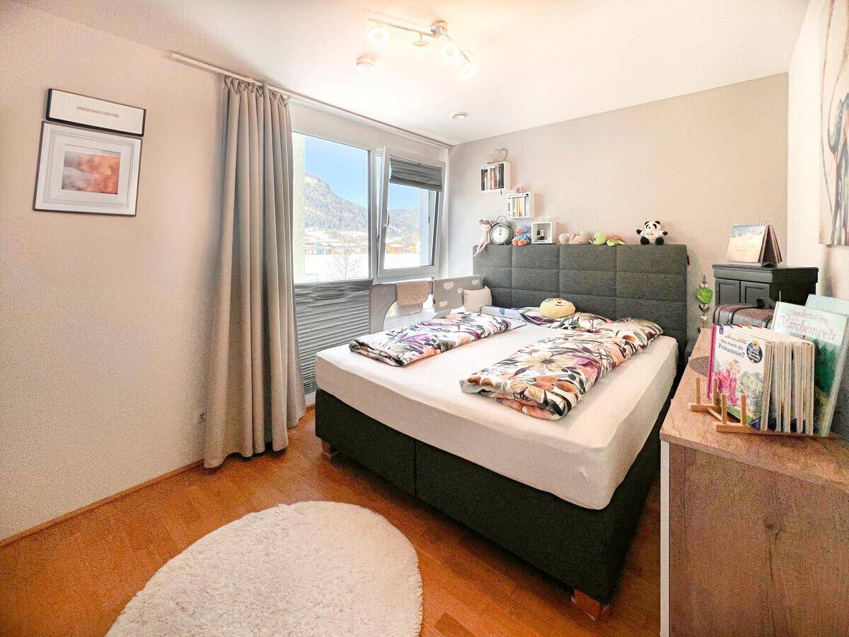 Helles Schlafzimmer mit Holzboden, bequemen Bett und Fenster mit Bergblick.