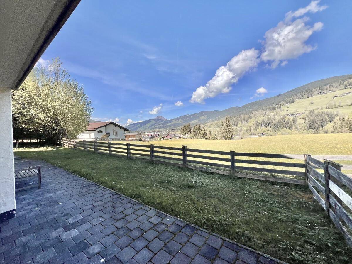 Gepflasterte Terrasse mit Blick auf grüne Wiesen und die umliegende Berglandschaft.
