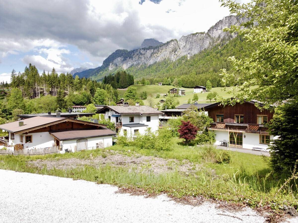 Blick über eine ländliche Siedlung mit Häusern und grüner Umgebung, umgeben von Bergen.