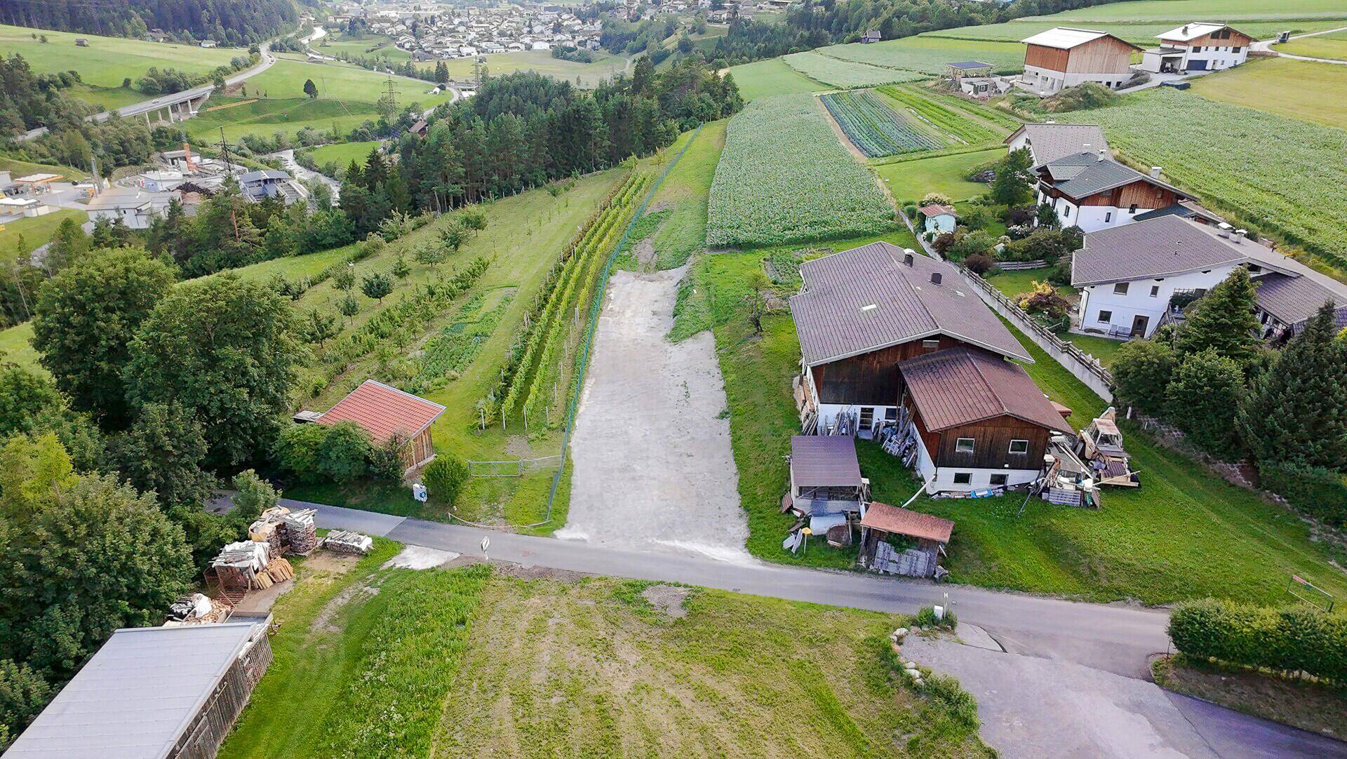 Luftaufnahme einer ländlichen Gegend mit Wohnhäusern, Feldern, Weinbergen und einer Zufahrtsstraße.