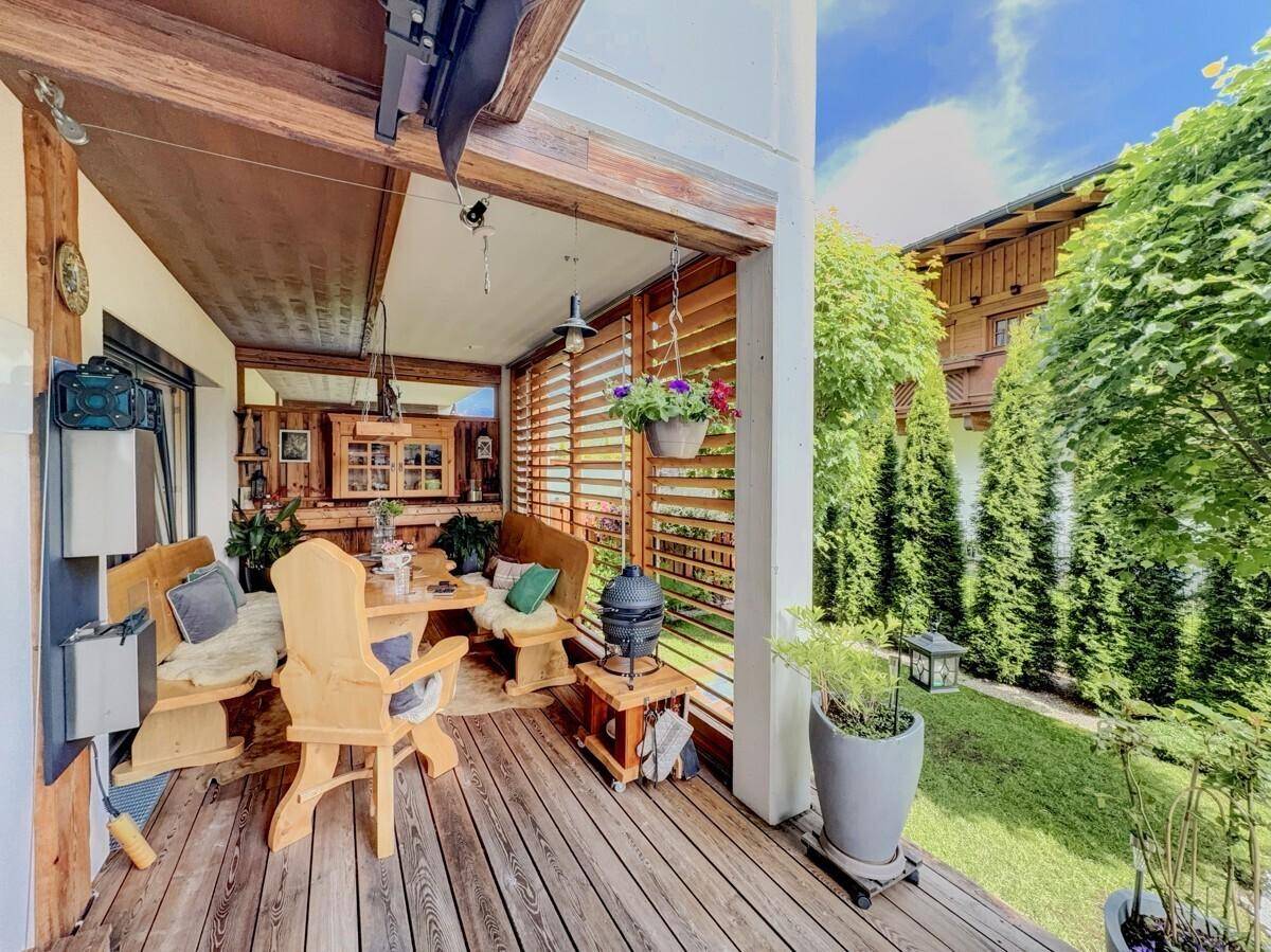 Gemütliche überdachte Loggia mit Holztisch und Bänken, ideal für Mahlzeiten im Freien.
