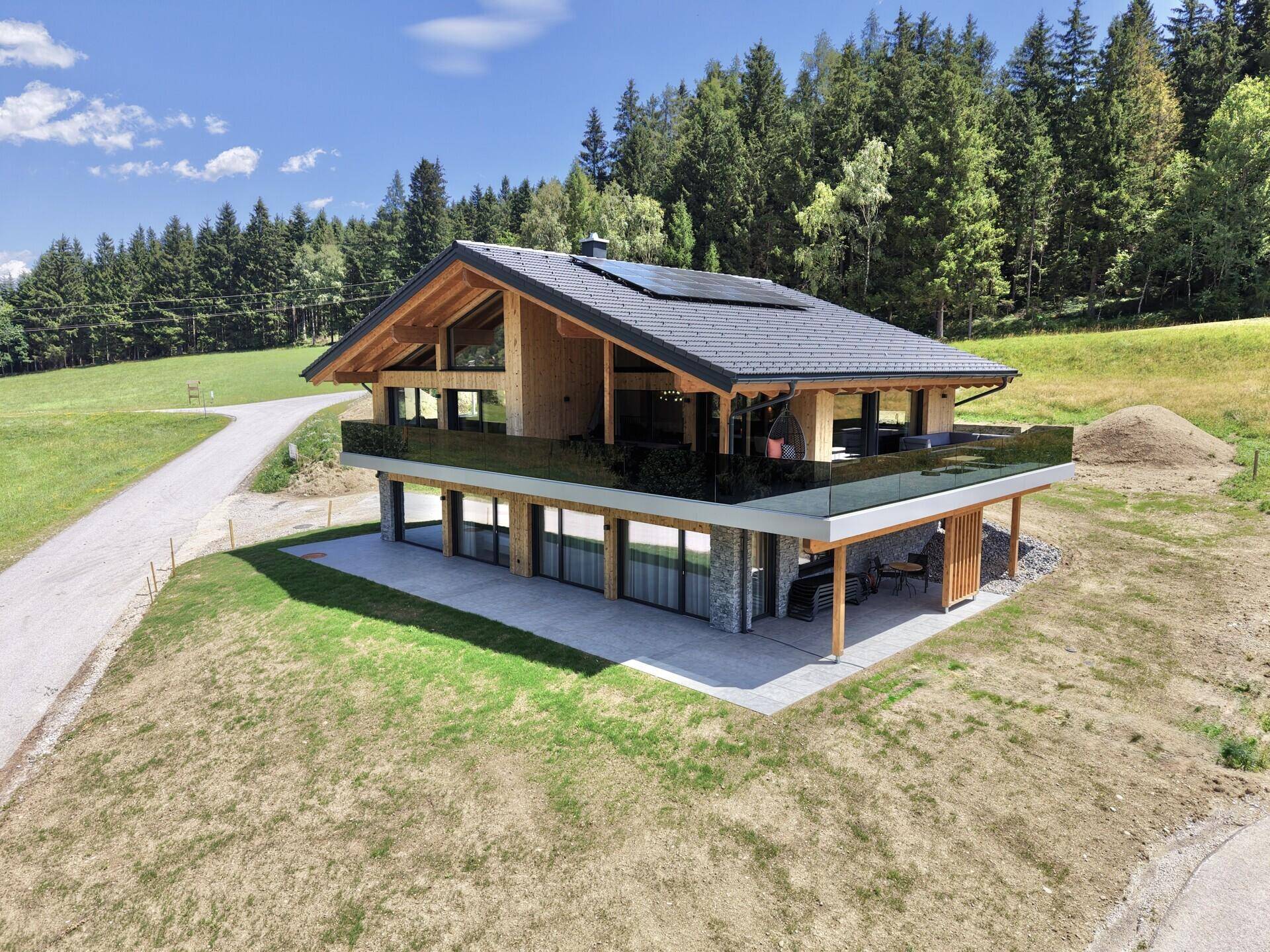 Modernes Chalet mit Holzfassade, Steinelementen und Solaranlage auf dem Dach.