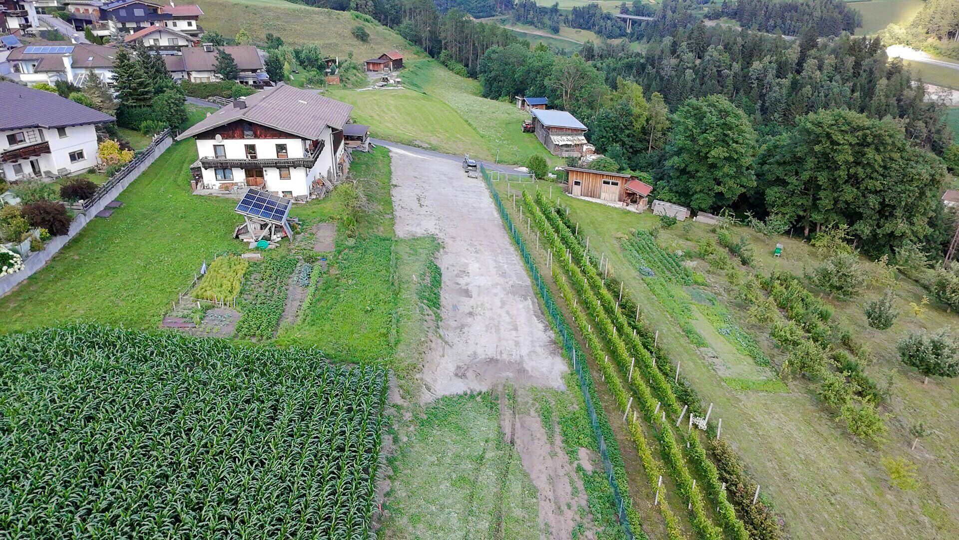 Weitläufige Luftaufnahme eines Grundstücks mit Haus, Feldern, Weinbergen und bewaldeten Hügeln.