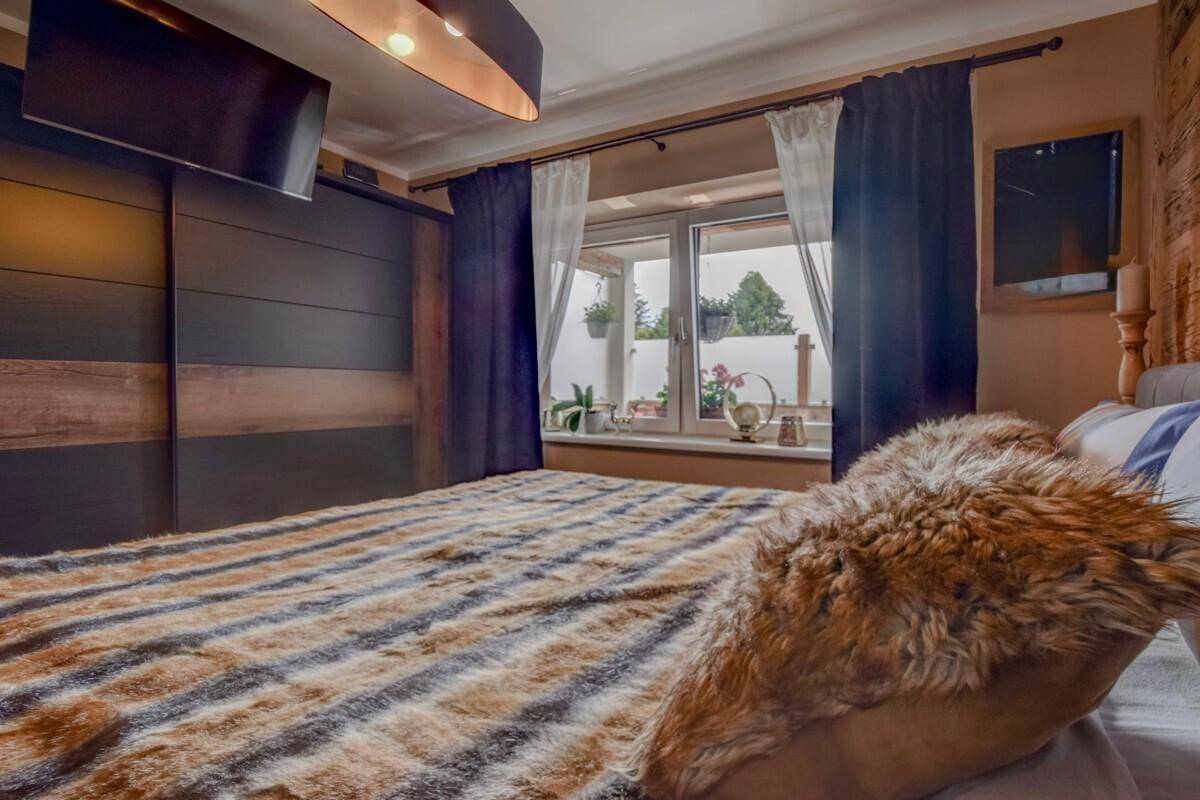 Schlafzimmer im Chalet-Stil mit großem Bett, Holzwand und Einbauschrank für viel Stauraum.