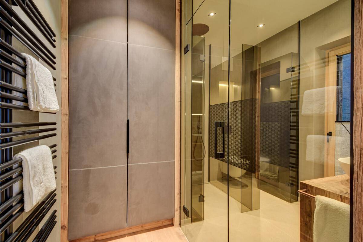 Modernes Badezimmer mit begehbarer Dusche, integrierten Schränken und beheiztem Handtuchhalter.