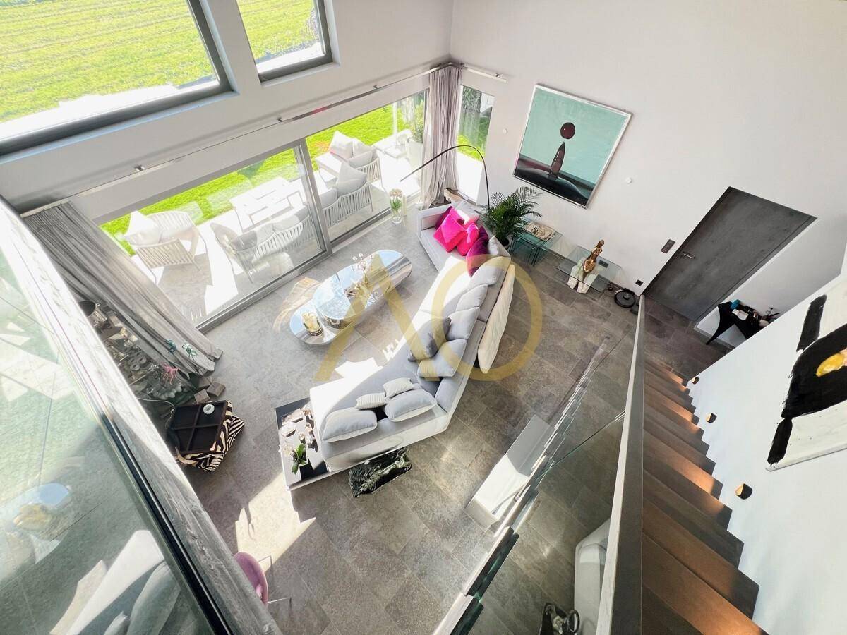 Blick von oben auf den offenen Wohnbereich mit großer Couch und viel Tageslicht.