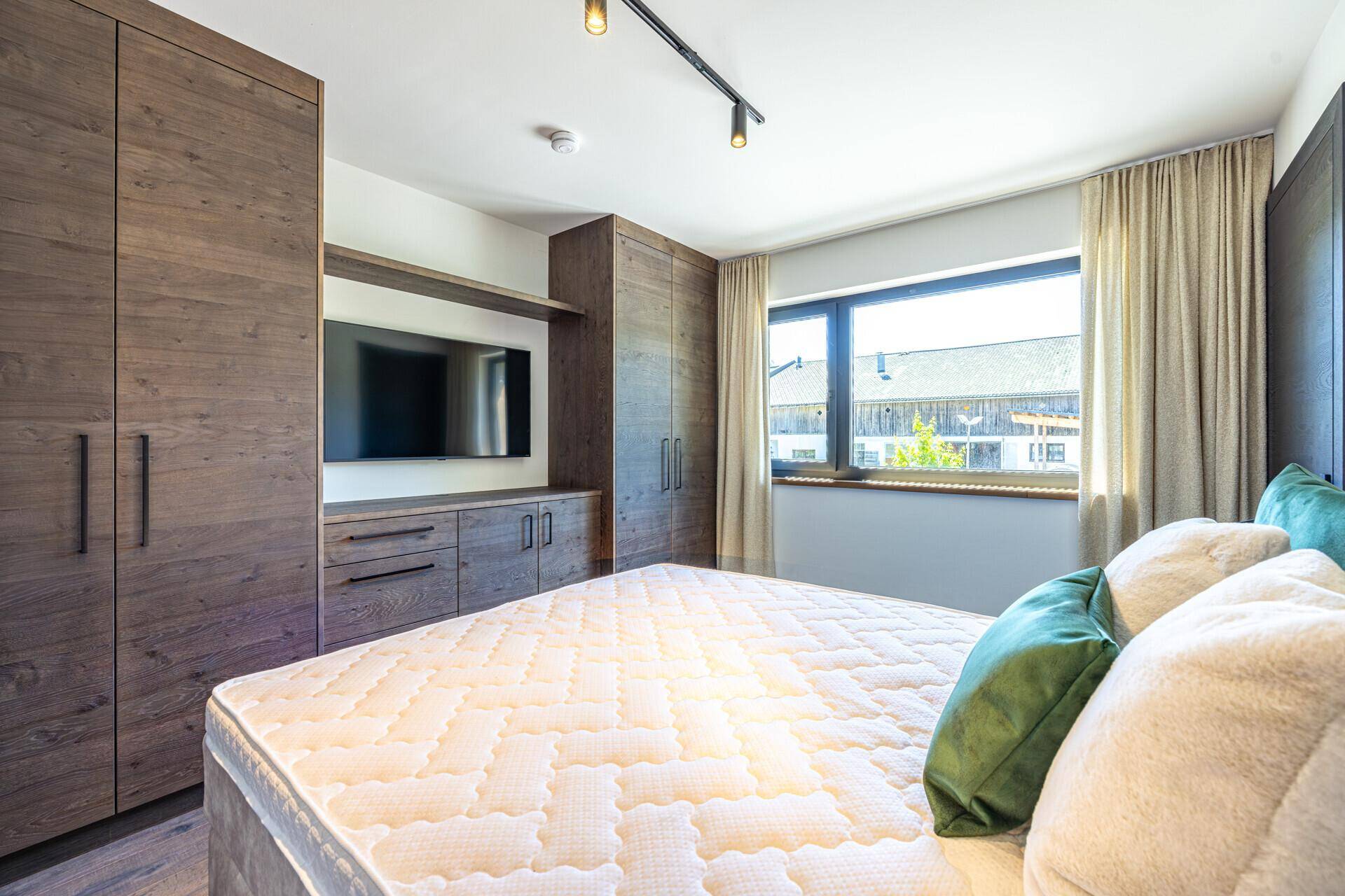 Komfortables Schlafzimmer mit Doppelbett, Einbauschränken und Fenster mit Blick ins Grüne.