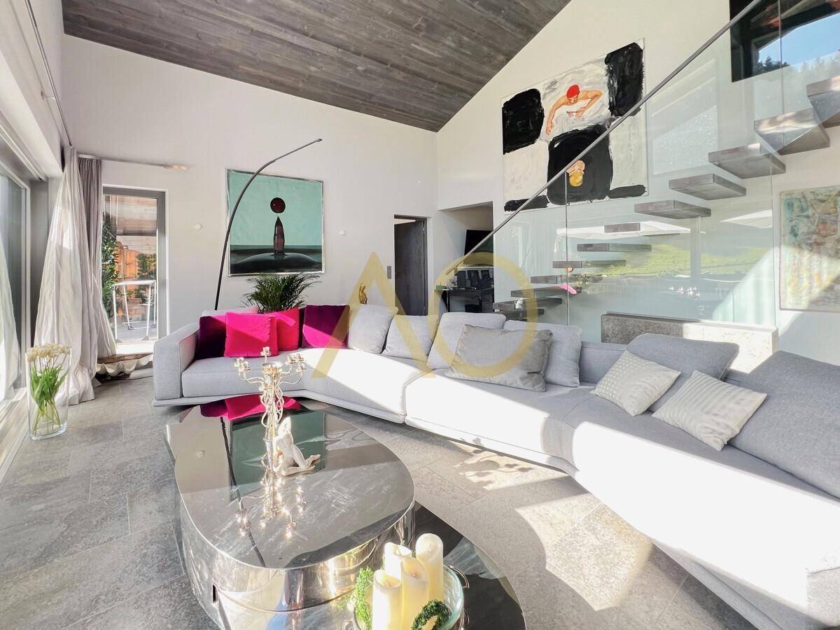 Stilvolles Wohnzimmer mit bequemer Couch, modernen Kunstwerken und viel Tageslicht.