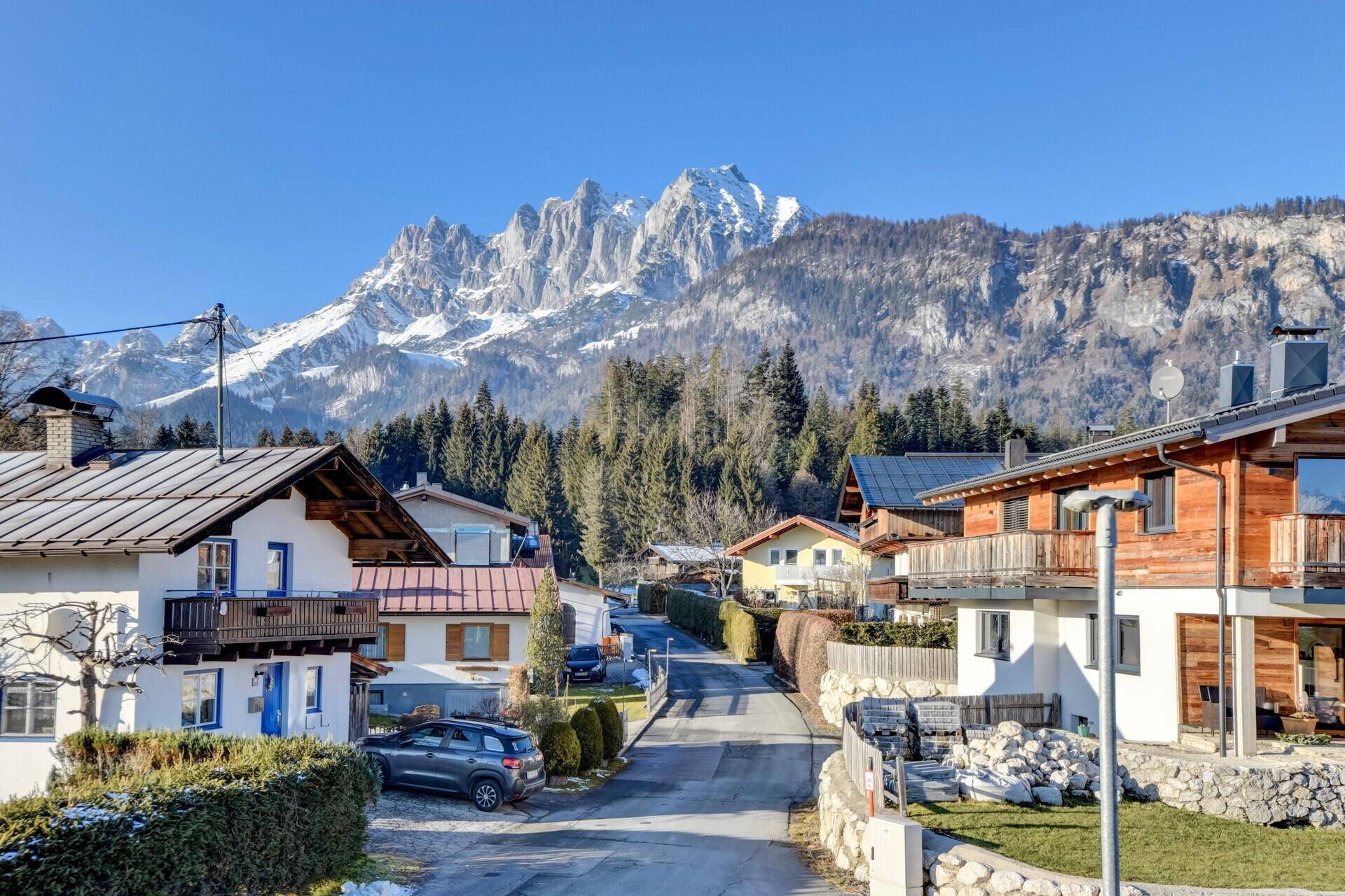 Malerische Wohngegend mit traditionellen Häusern und Bergblick an einem sonnigen Tag.