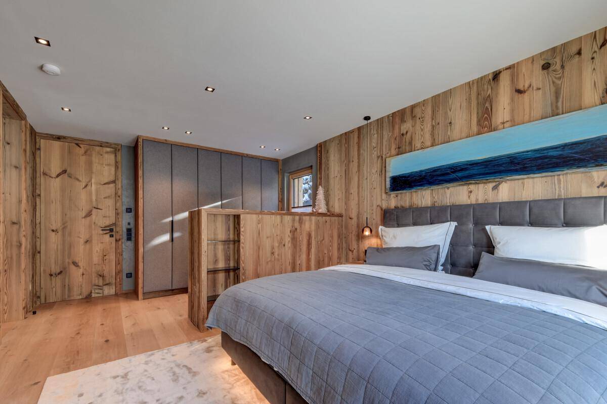 Helles Schlafzimmer mit Holzwand, großem Bett und Einbauschränken.