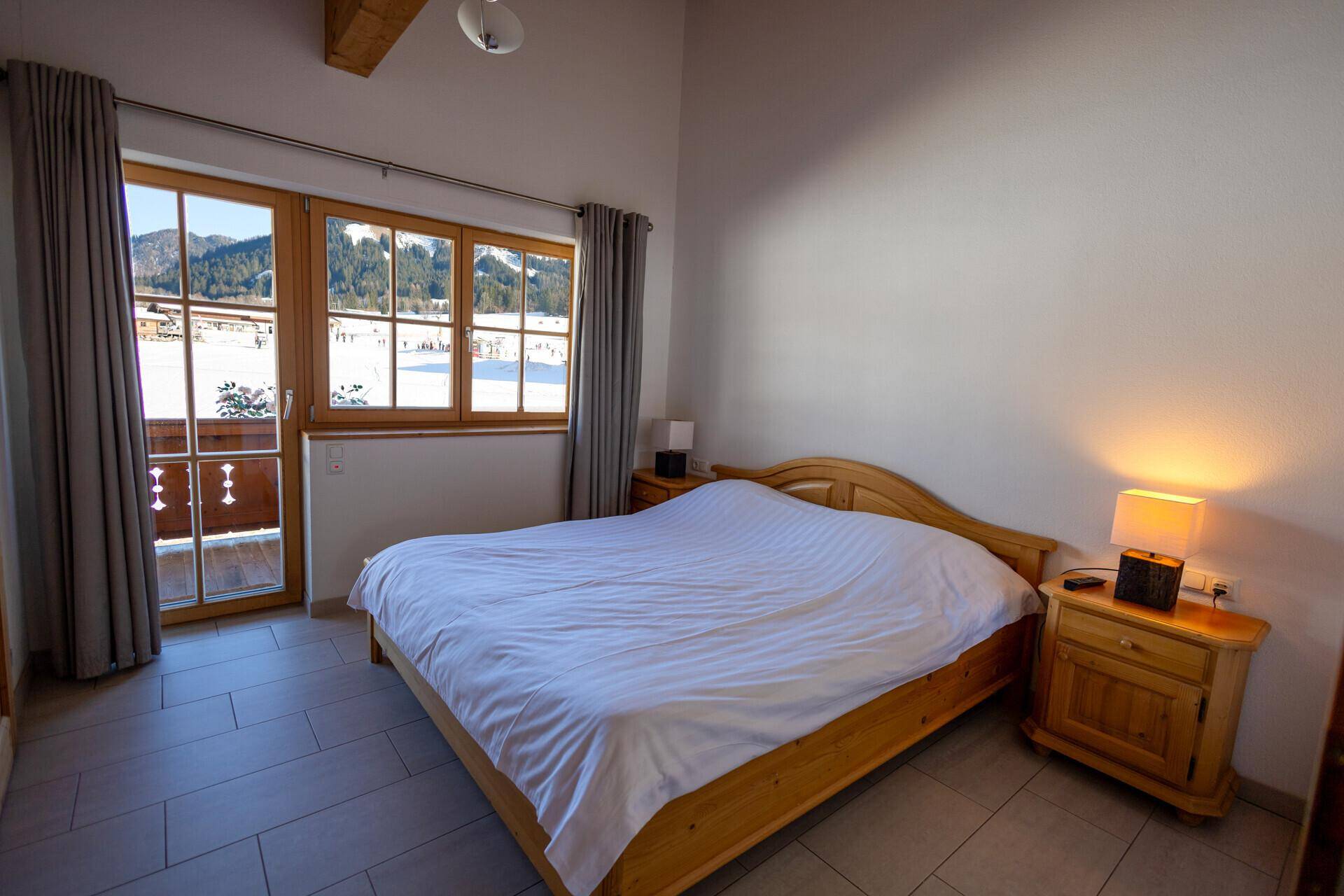 Helles Schlafzimmer mit Doppelbett, Balkonzugang und herrlichem Bergblick.