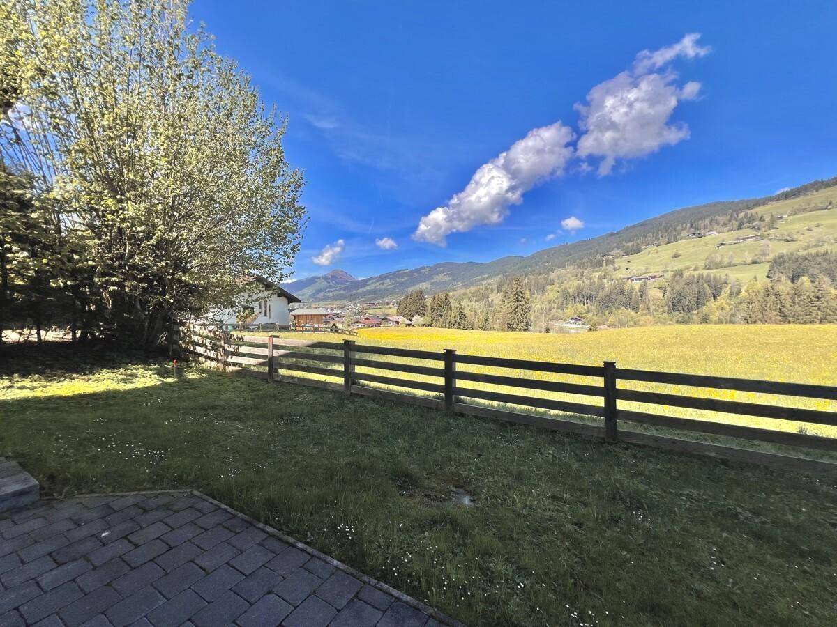 Grüner Garten mit Holzzaun und weitem Blick auf die umliegende Berglandschaft.