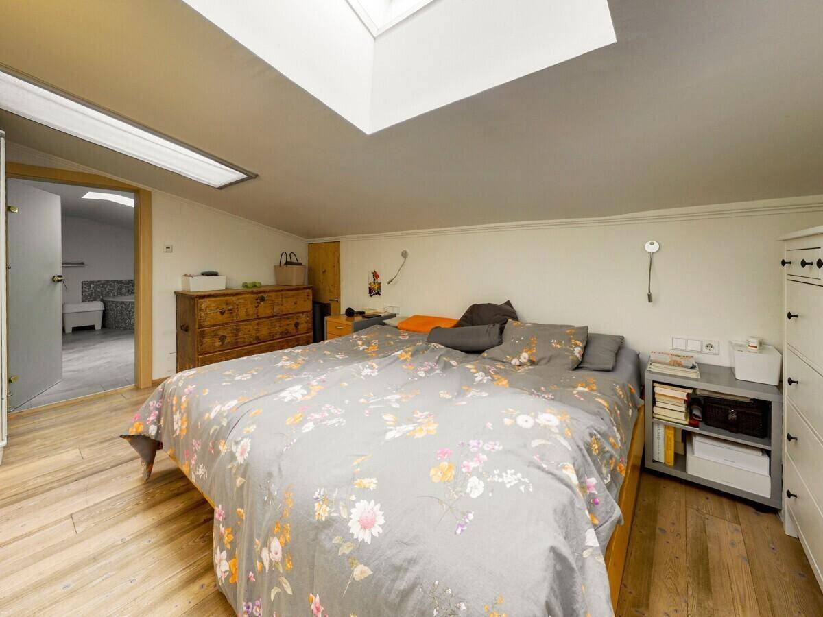 Gemütliches Schlafzimmer mit Holzboden, Dachschräge und Oberlicht für natürliches Licht.