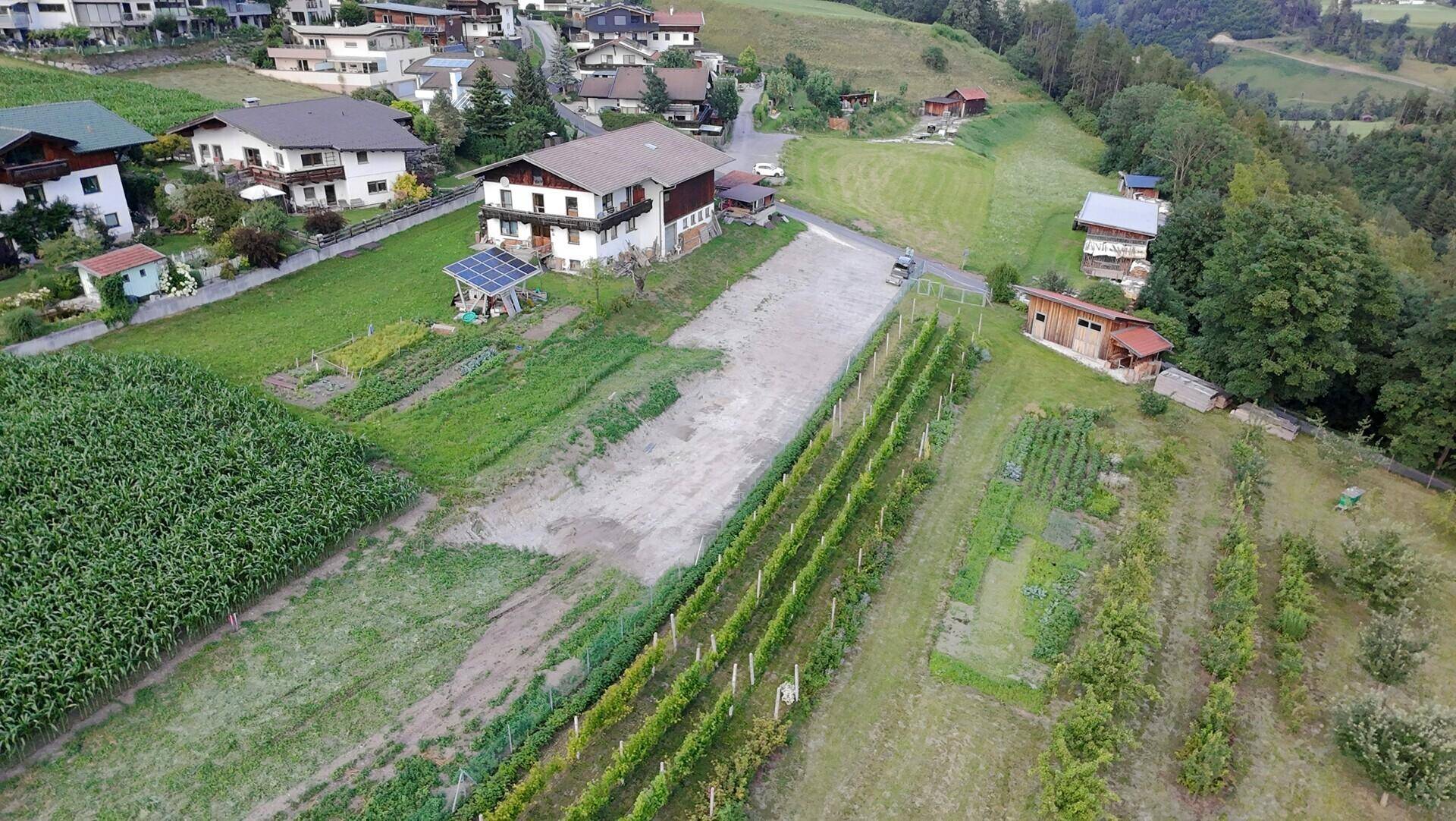 Luftaufnahme einer ländlichen Gegend mit Feldern, Weinbergen, Häusern und einem Solarsystem.