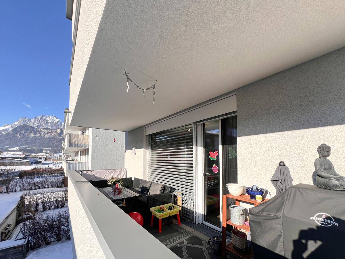 Sonniger Balkon mit Bergblick, Sitzgelegenheiten und Grillbereich, ideal für entspannte Stunden im Freien.