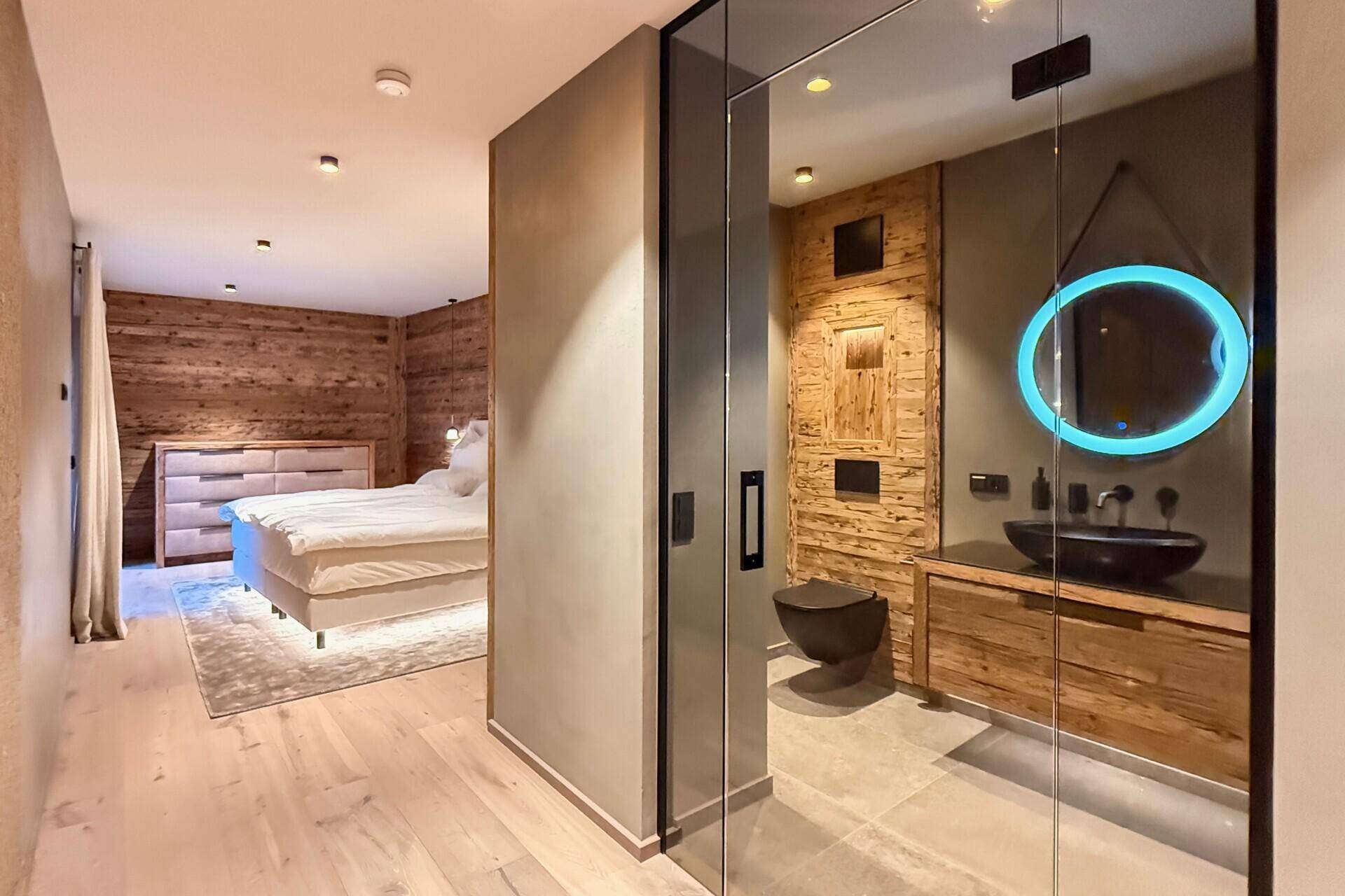 Schlafzimmer mit offenem Badbereich, Holzwänden und moderner Ausstattung, hell und geräumig.