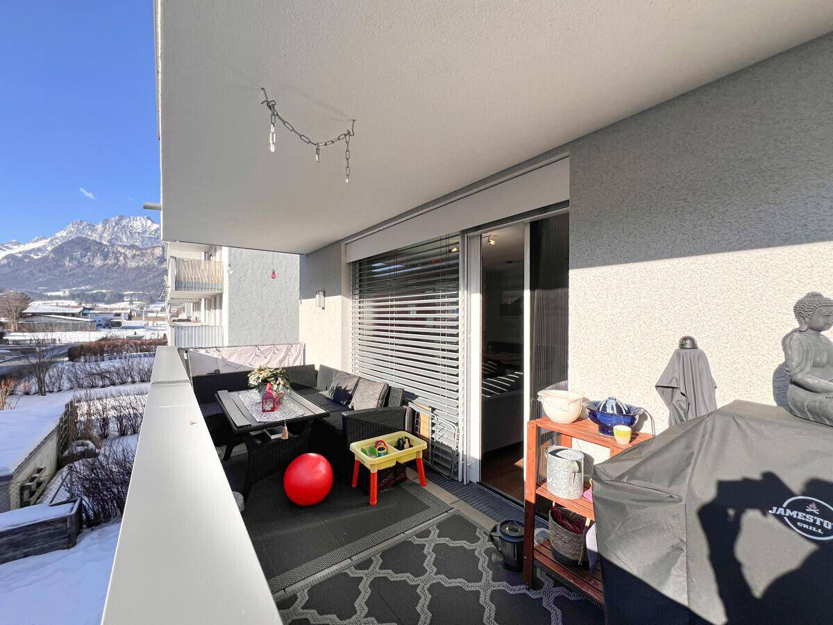 Breiter Balkon mit gemütlicher Sitzecke, Grill und Panoramablick auf die Berge.