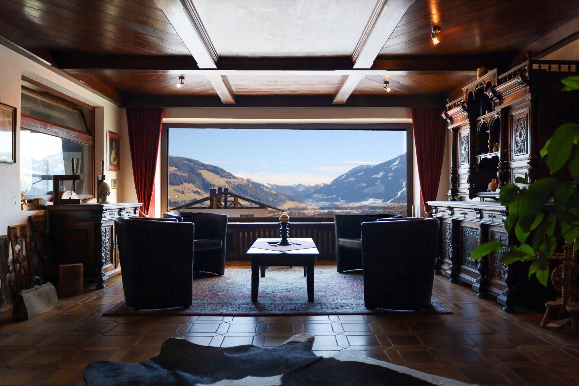 Gemütliches Wohnzimmer mit großem Panoramafenster, das einen atemberaubenden Blick auf die Berge bietet.