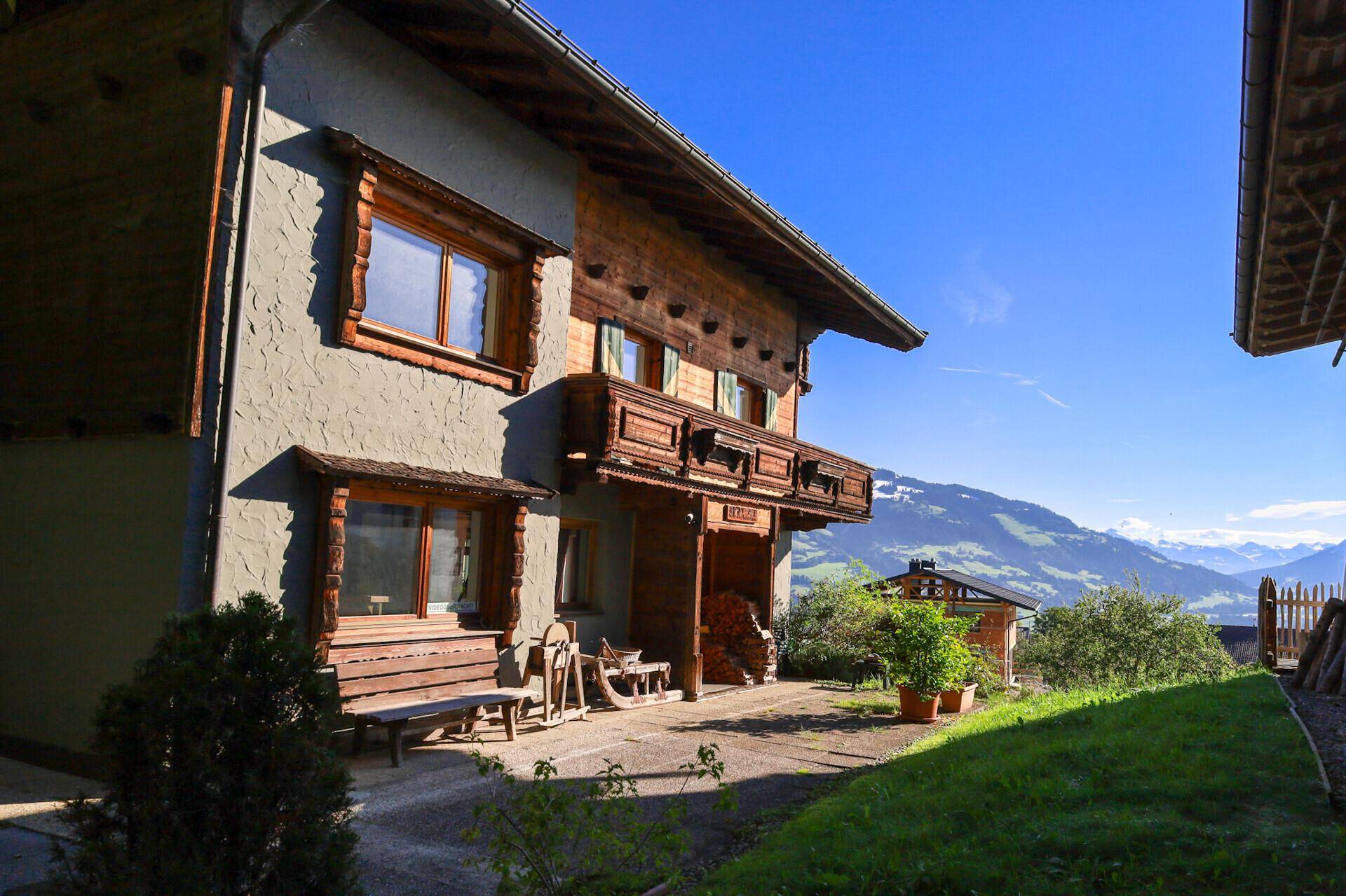 Traditionelles Haus mit Holzbalkon und Fassadendetails, eingebettet in eine malerische Berglandschaft.