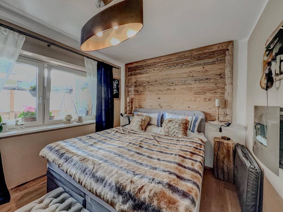 Schlafzimmer im Chalet-Stil mit Holzwand, bequemen Bett und dekorativem Kamin an der Wand.