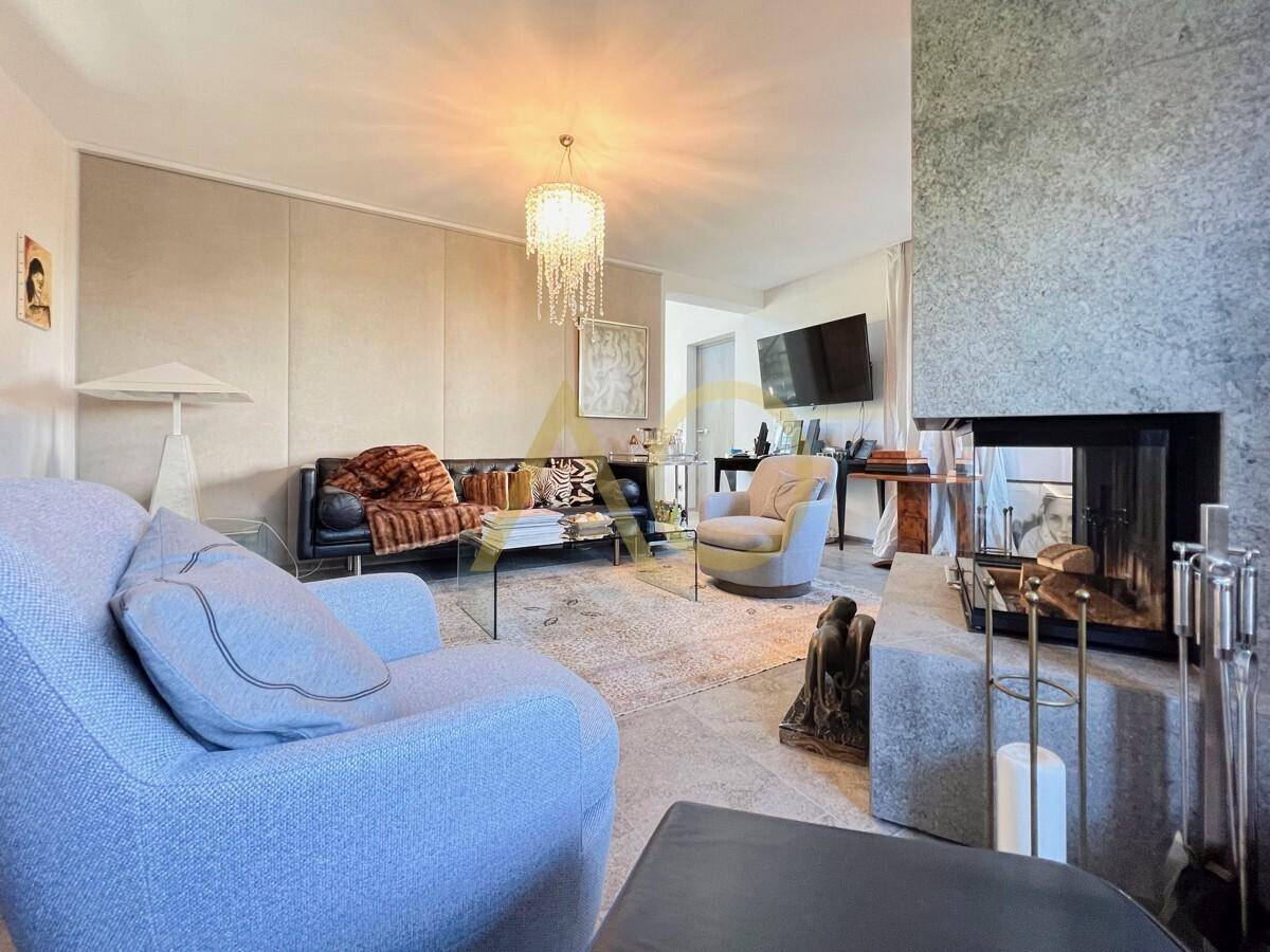 Helles Wohnzimmer mit Kamin, modernen Möbeln und Blick auf die Umgebung.