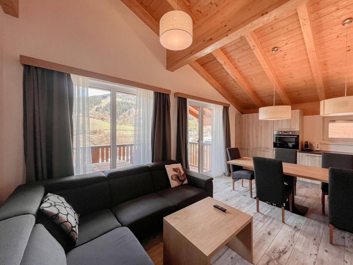 Gemütlicher Wohnbereich mit großem Sofa, Esstisch und Zugang zu einem sonnigen Balkon.