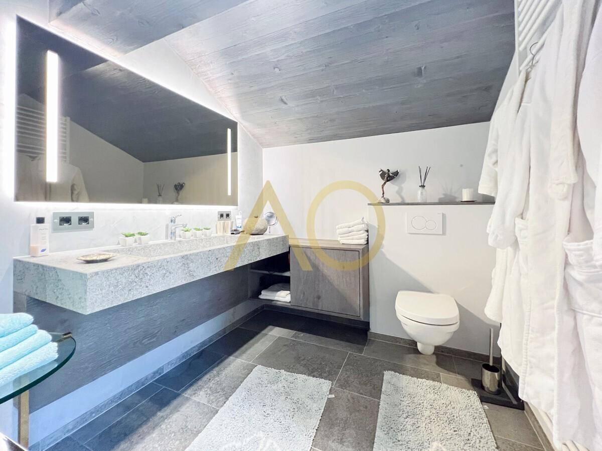Modernes Badezimmer mit Doppelwaschtisch, beleuchtetem Spiegel und Wand-WC.