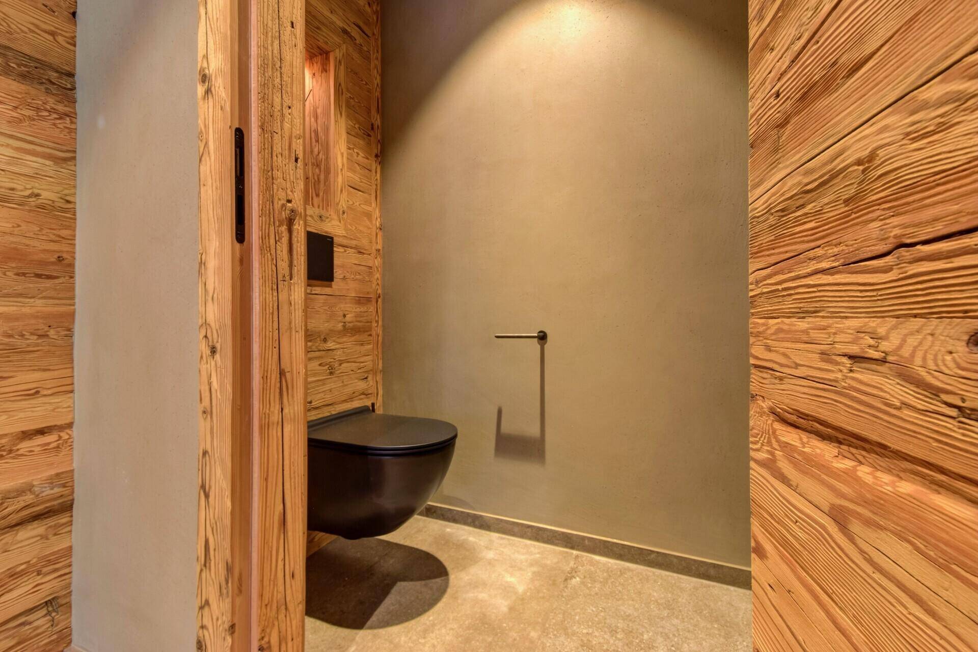 Modernes Gäste-WC mit dunkler Toilette und Holzwänden, minimalistisch und stilvoll gestaltet.