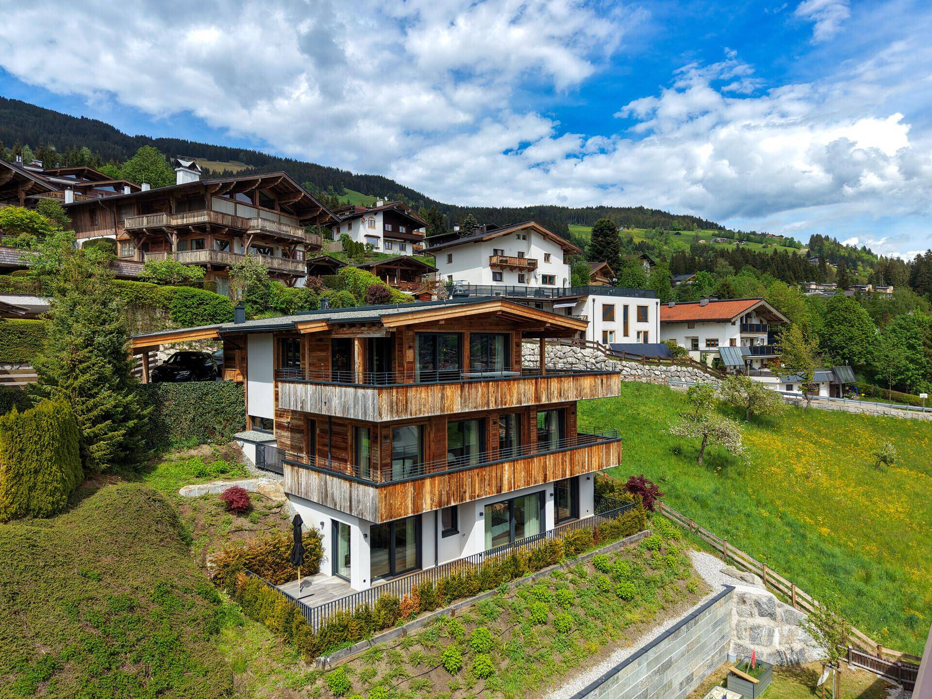 Attraktives Holzchalet mit mehreren Etagen und Terrassen, umgeben von grüner Natur.