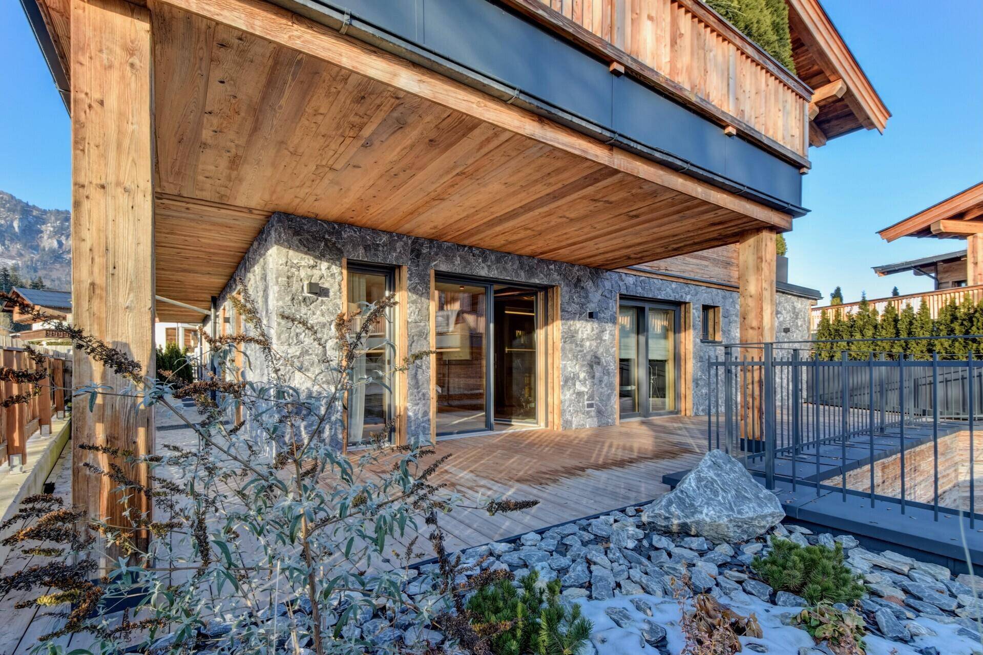 Erdgeschoss-Terrasse mit Holzdeck und Steinelementen, umgeben von winterlicher Vegetation.