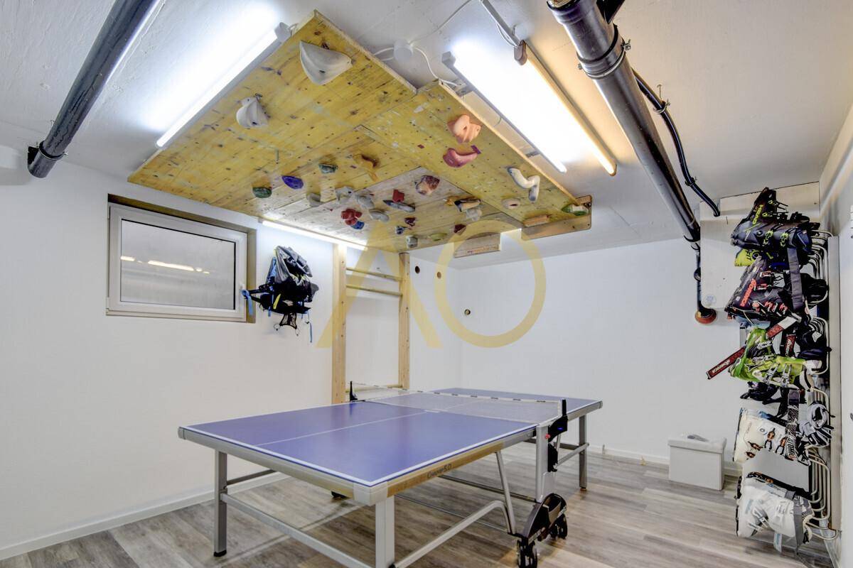 Vielseitiger Freizeitraum mit Kletterwand, Tischtennisplatte und sportlichen Geräten.