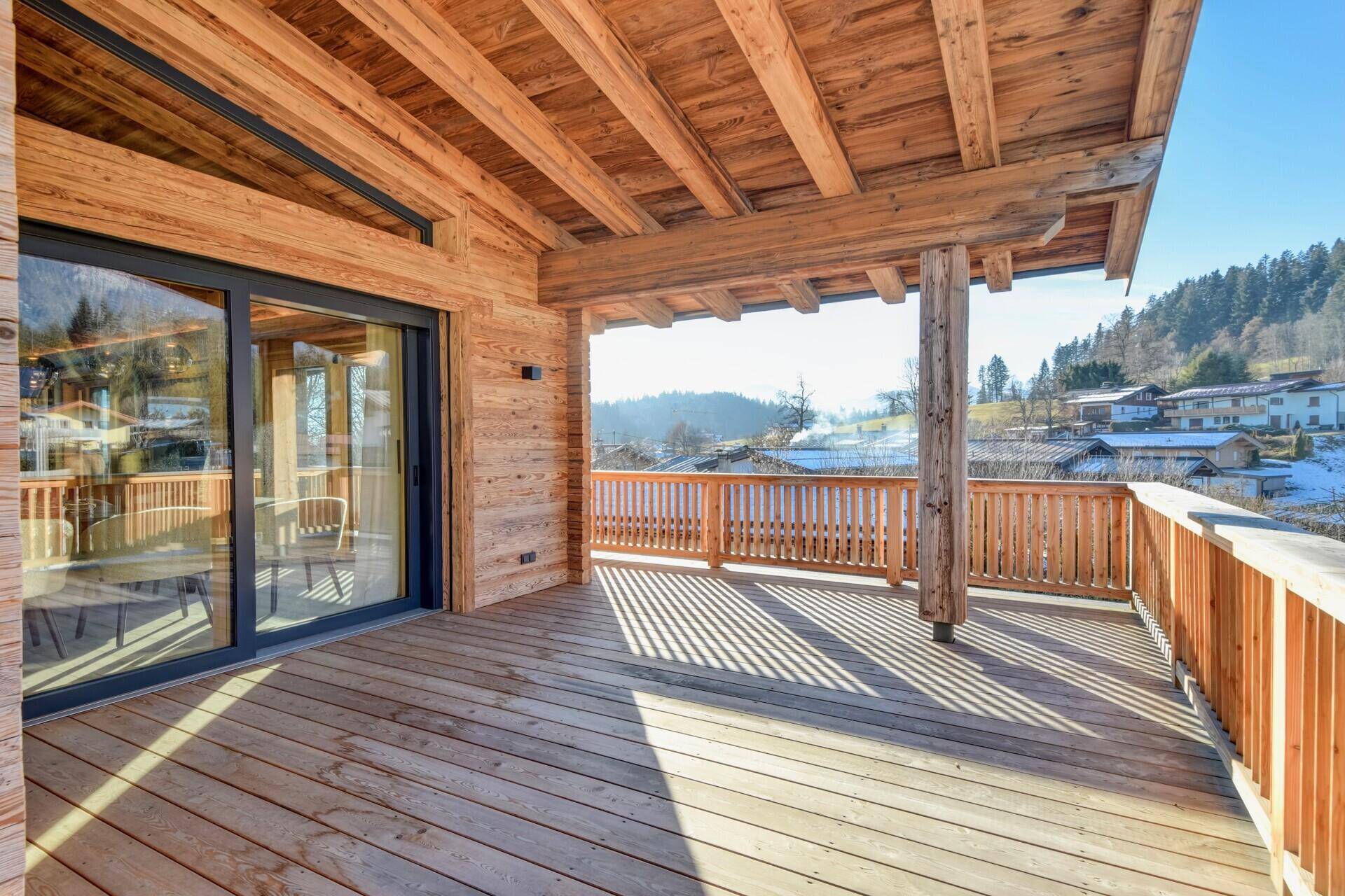 Großer Holzbalkon mit Bergblick und viel Sonnenschein, ideal zum Entspannen im Freien.