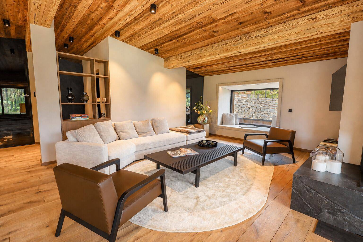 Geräumiges Wohnzimmer mit Holzbalkendecke, bequemen Sofas und einem gemütlichen Fensterplatz.