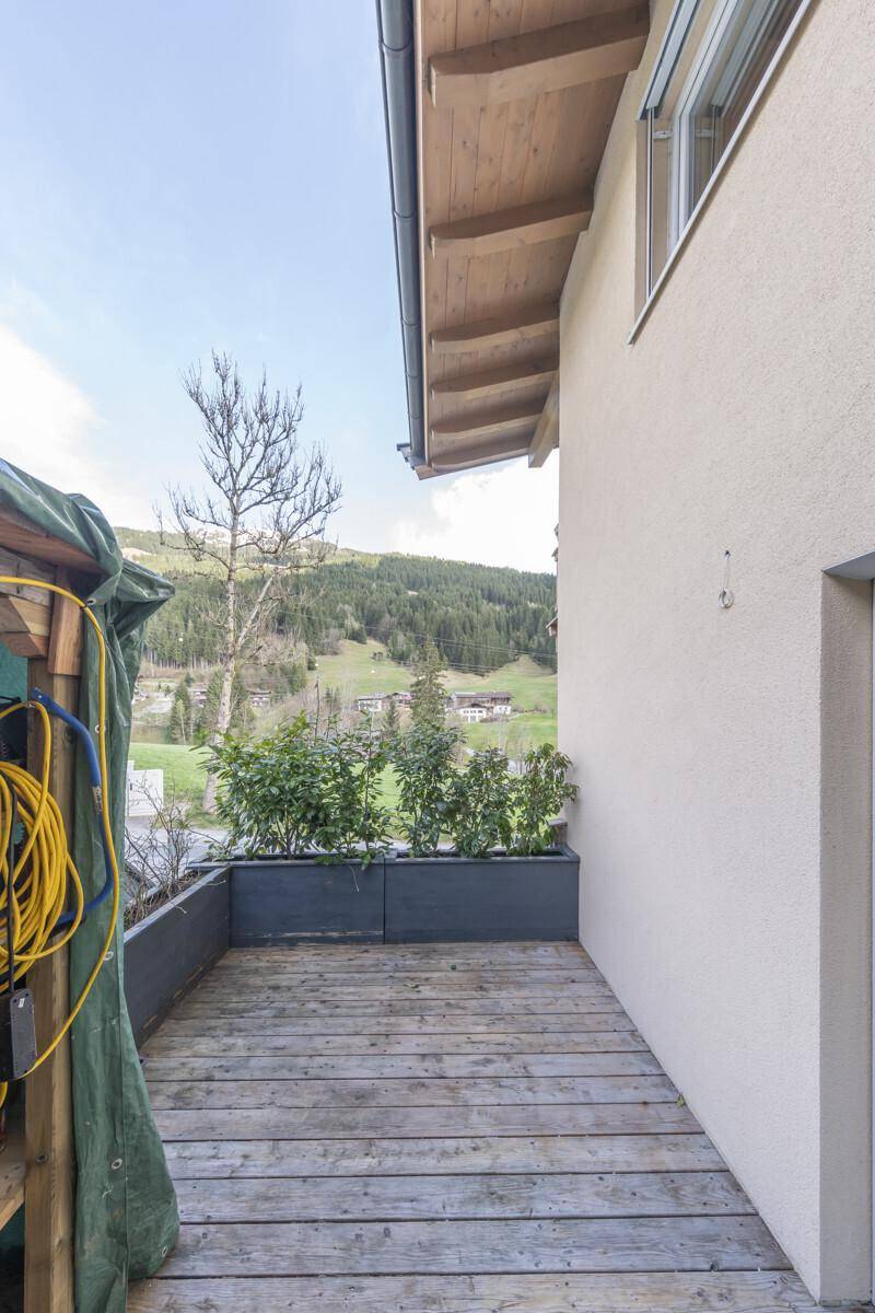 Kleiner Holzbalkon mit Blick auf die grüne Umgebung und die Berge.