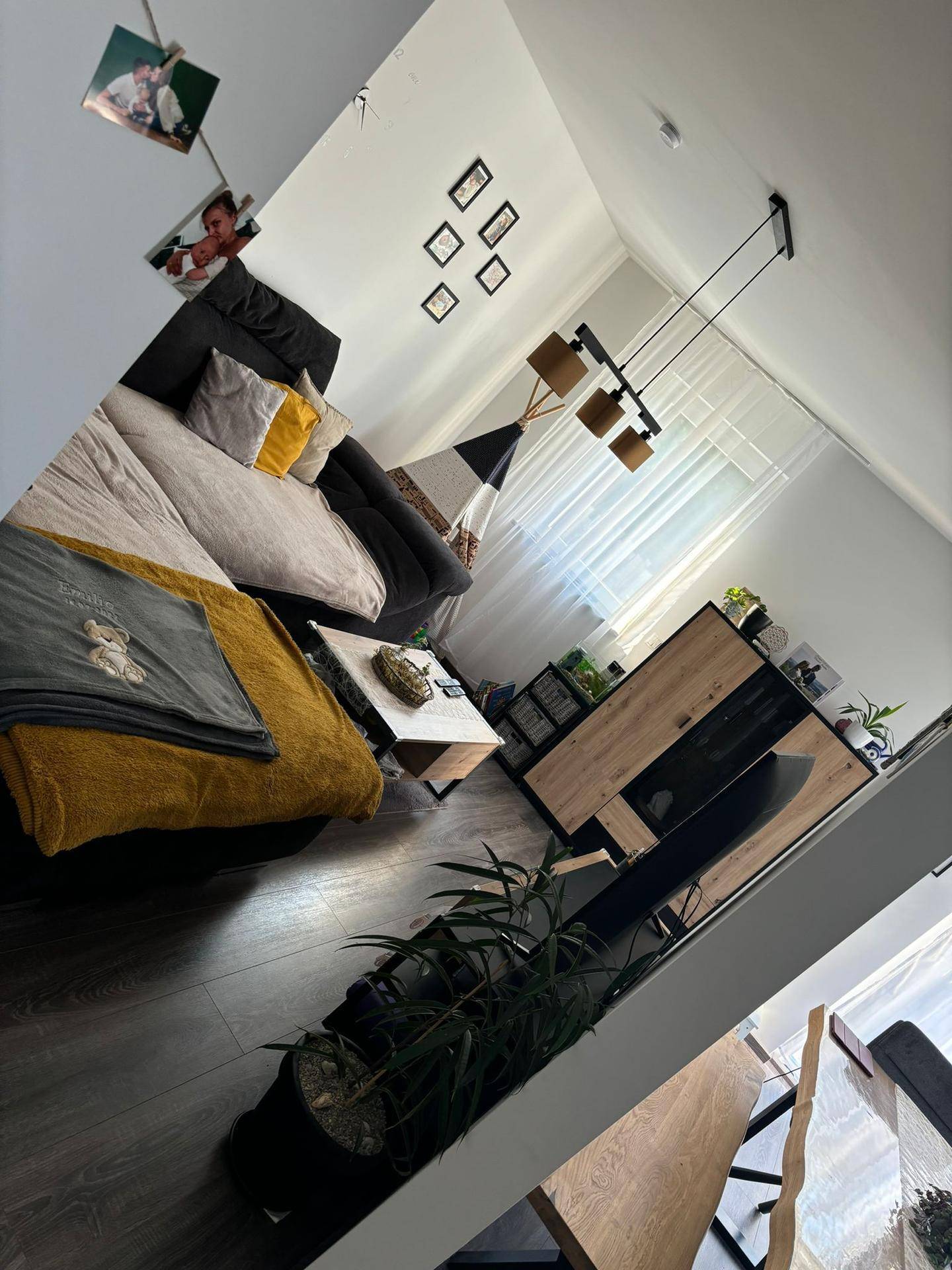 Gemütliches Wohnzimmer mit Sofa, modernem Sideboard und dunklem Laminatboden.