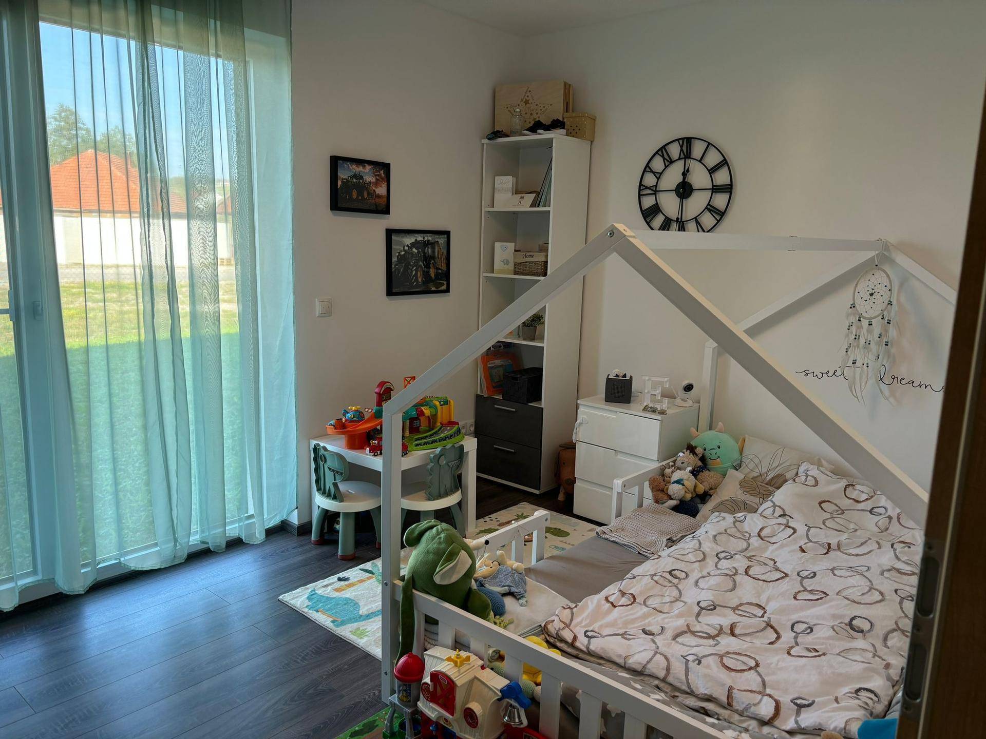 Kinderzimmer mit hellem Holzbett, Spielbereich und großem Fenster zum Garten.