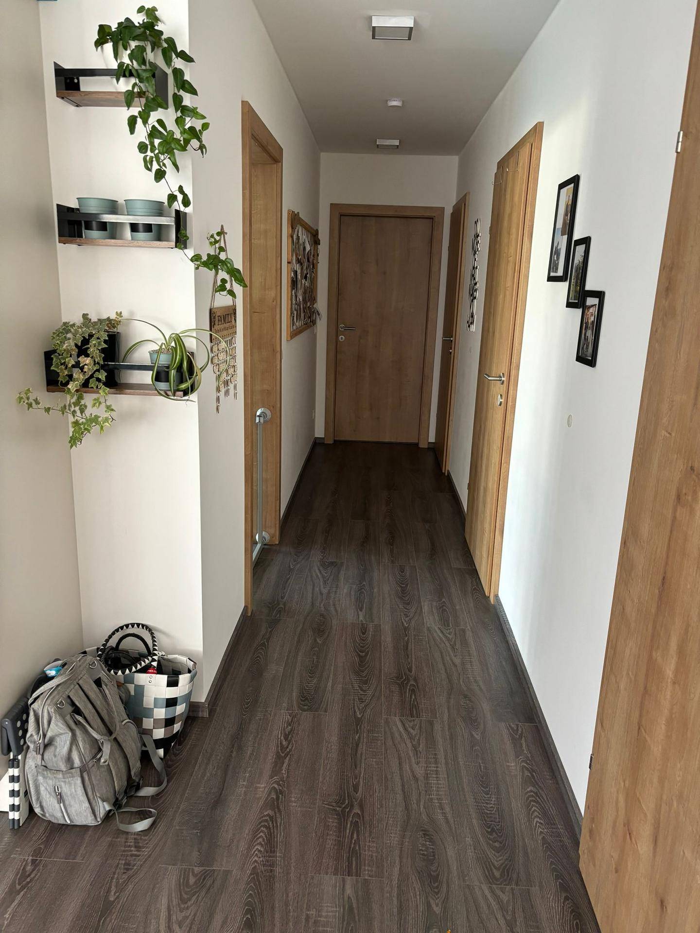Heller Flur mit dunklem Laminatboden und Holztüren, der zu den Zimmern führt.