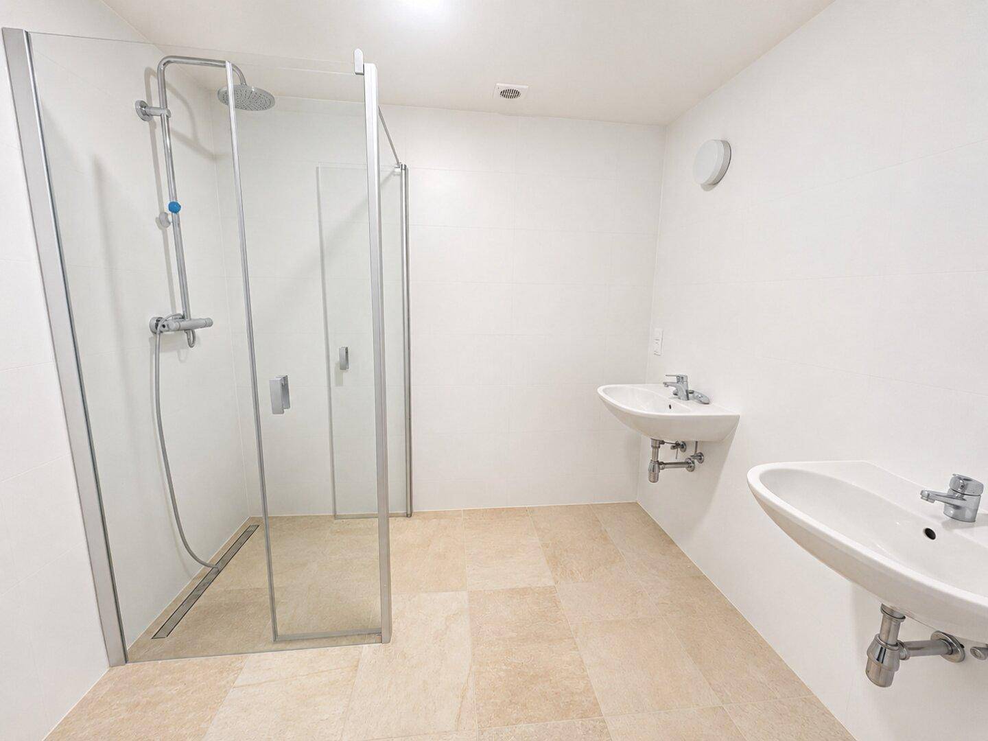 Geräumiges Badezimmer mit ebenerdiger Regendusche und zwei modernen Waschbecken.