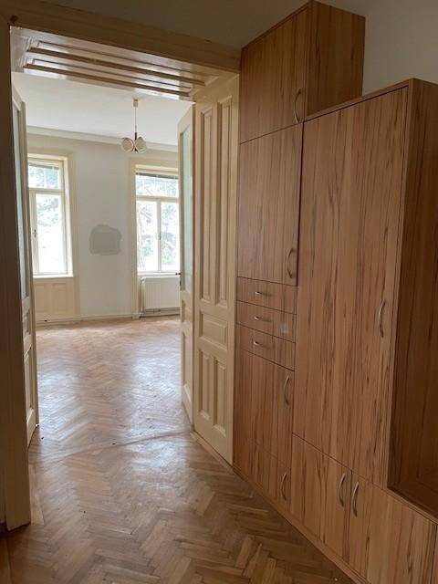 Heller Flur mit Holzschränken und Fischgrätparkett, der zu einem weiteren Zimmer führt.