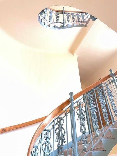 Elegantes Treppenhaus mit kunstvollen schmiedeeisernen Geländern und einem geschwungenen Holzhandlauf.
