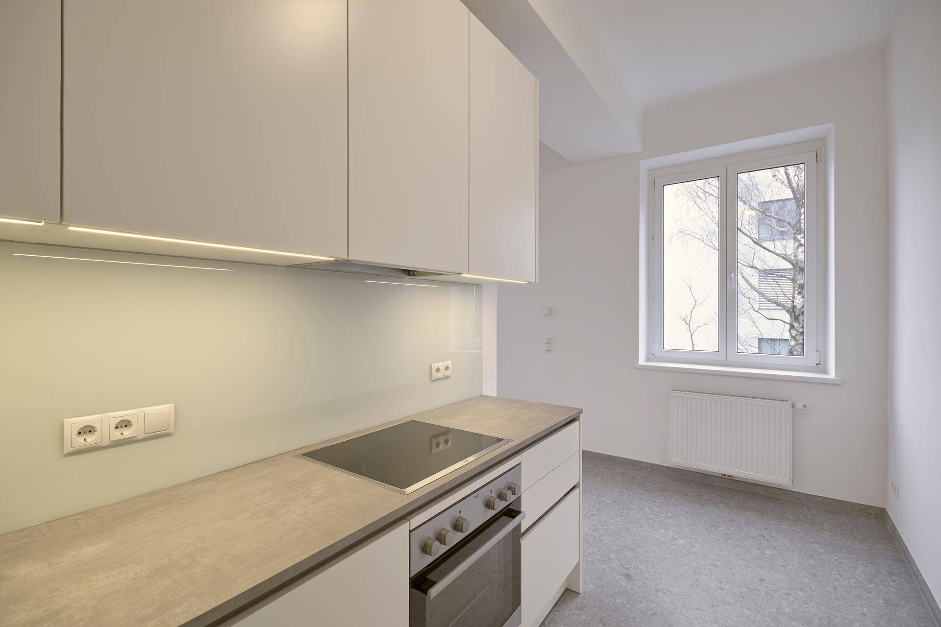 Nahaufnahme der Küchenzeile mit Kochfeld, Spüle und weißen Oberschränken, in einem modernen Design.