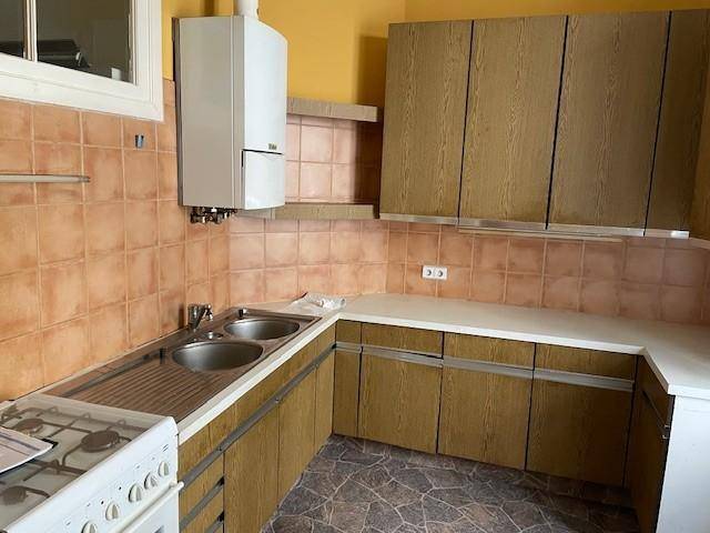 Funktionale Küche mit Holzschränken, Gasherd und Wandfliesen in warmen Farbtönen.