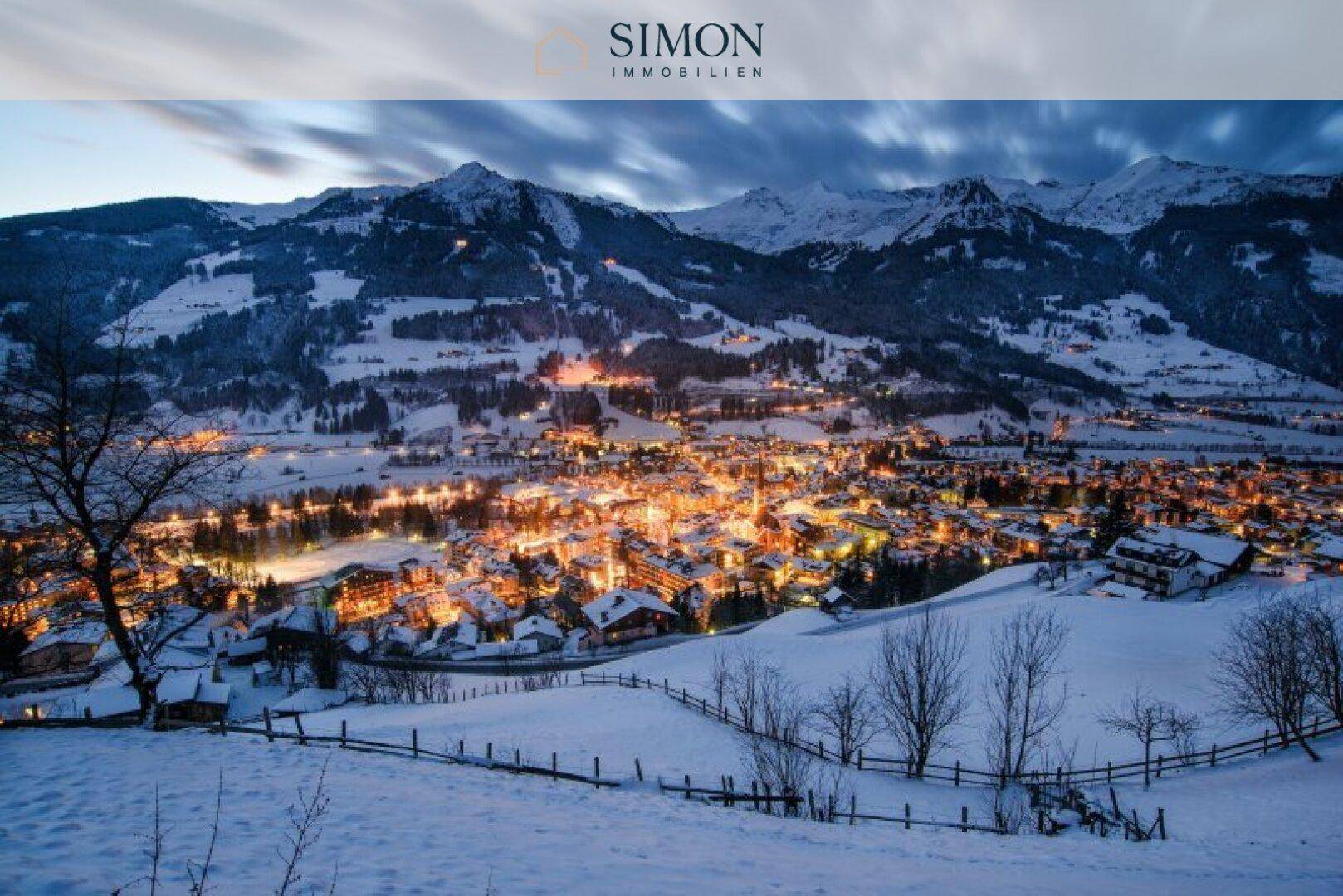 Winterliche Abendansicht einer beleuchteten Stadt in den verschneiten Bergen.