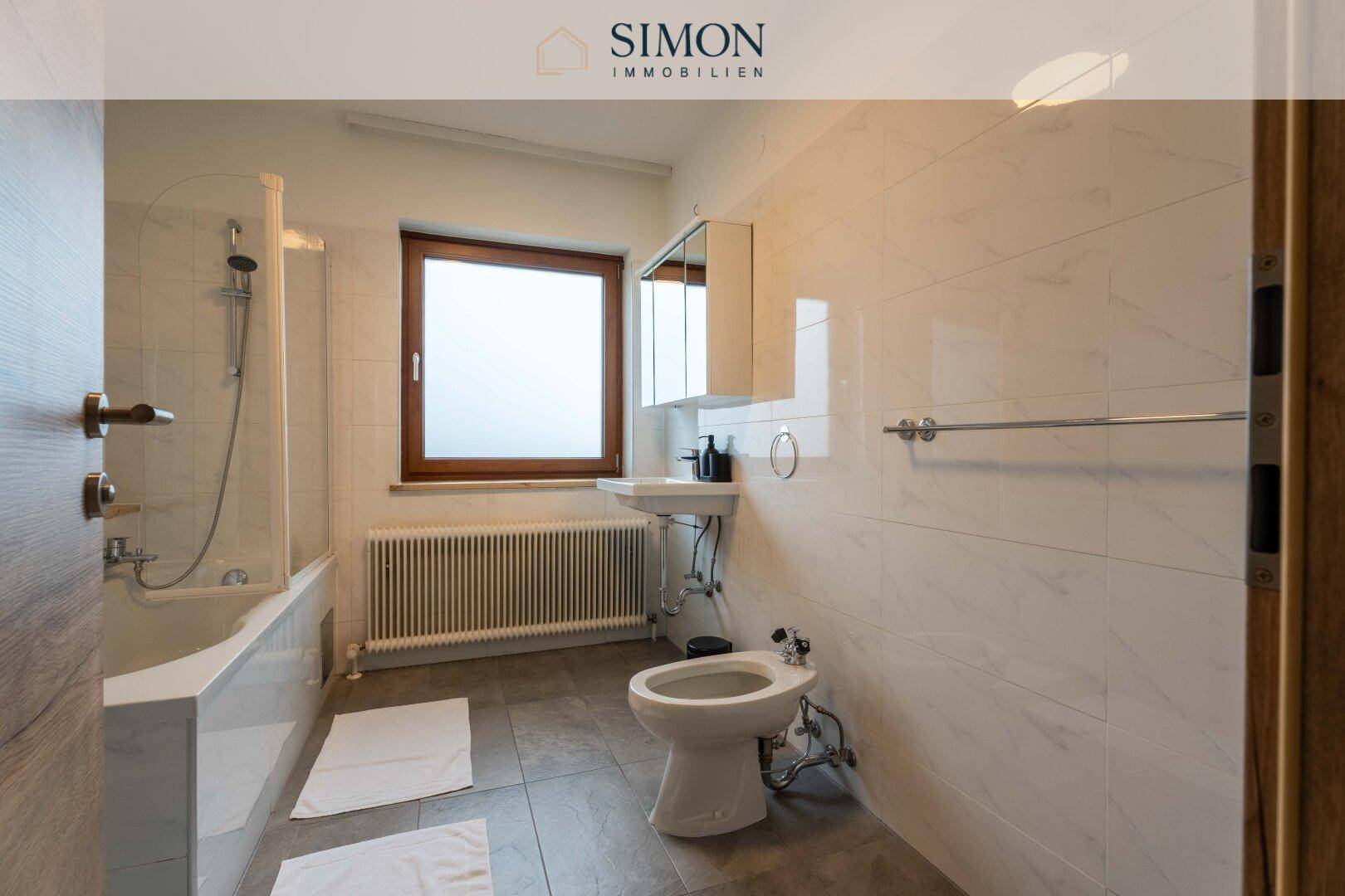 Badezimmer mit Badewanne, Dusche, Bidet und Fenster für natürliche Belüftung.
